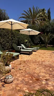 two umbrellas and lounge chairs on a patio at Dar Nadim sur le Golf de Samanah in Marrakech