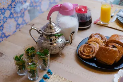 a table with a tea kettle and a plate of food at Riad Lkhlil in Marrakech