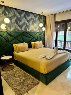 a bedroom with a large bed with a green headboard at Plaza Guéliz Prestige Apartment in Marrakech