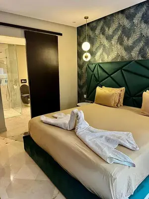 a white towel laying on a bed in a room at Plaza Guéliz Prestige Apartment in Marrakech