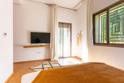 a bedroom with a bed and a tv on a wall at Villa 5 Suites Modern with Ping Pong table and Heated Swimming pool in Marrakech