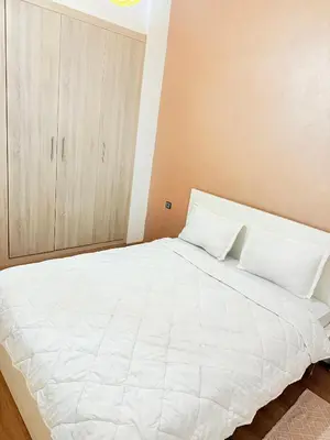 a bedroom with a large white bed with a cabinet at Appart Abir2 N1 Confort Au Centre-ville in Marrakech