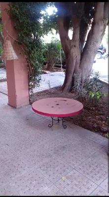 a red surfboard sitting on a table next to a tree at Chambre individuelle in Marrakech