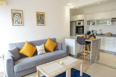a living room with a couch and a kitchen at Cosy cocon au coeur de Gueliz-Parking gratuit in Marrakech