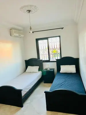 a bedroom with two beds and a table and two windows at Marrastay in Marrakech