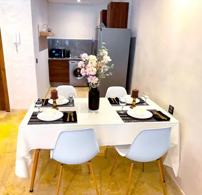 a dining room table with white chairs and flowers on it at Appartement cosy Marrakech in Marrakech
