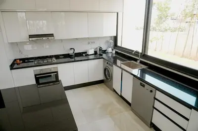 a kitchen with white cabinets and a sink and a window at Villa émeraude - Route Ourika in Marrakech