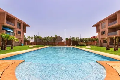 a large swimming pool in a yard next to a building at Wonderful apartment with garden and large pool in Marrakech