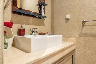 a bathroom with a white sink and a mirror at Wonderful apartment with garden and large pool in Marrakech