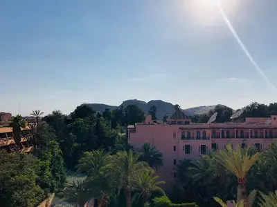 a large pink building with palm trees and mountains in the background at Modern apartment centre ville in Marrakech