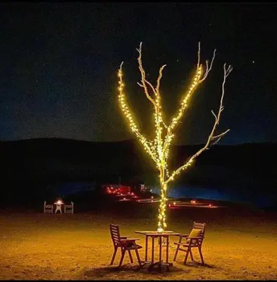 a table with two chairs and a tree with lights at Marrakech appartement in Marrakech