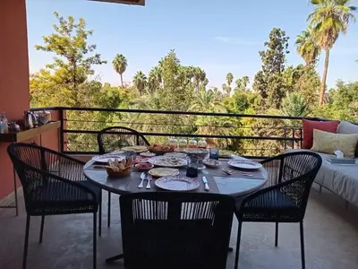 a table with chairs and food on a balcony at Magnifique appartement in Marrakech