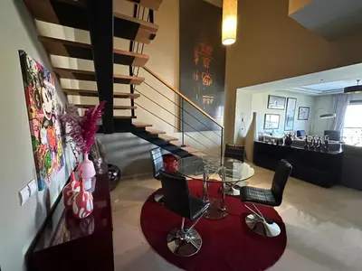 a room with a table and chairs and a staircase at Duplex à l hivernage in Marrakech