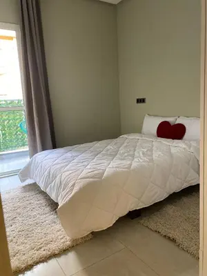 a bedroom with a white bed with a red heart pillow at Appartement Idéal pour Votre Séjour in Marrakech