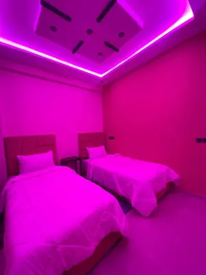 two beds in a room with pink lighting at Appartement Idéal pour Votre Séjour in Marrakech