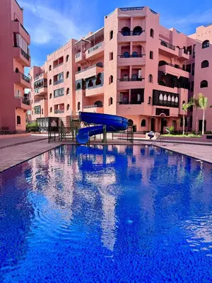a slide in a swimming pool in front of a building at RENTSUITE APPARTEMENT Premium Village Luxurious Residence in Marrakech