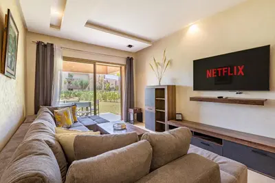 a living room with a couch and a tv at Luxury Garden-Level Apartment with Poolside Serenity in Marrakech