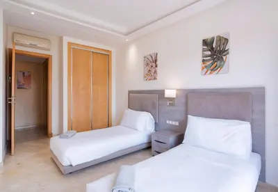a hotel room with two beds with white sheets at Appart Hyper-Centre Gueliz - Wifi - Netflix in Marrakech