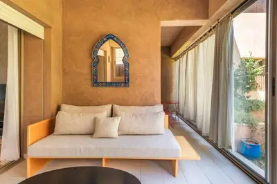 a living room with a couch and a mirror at Apart Confort Rez-de-Jardin Piscine Wi-Fi Terrasse in Marrakech