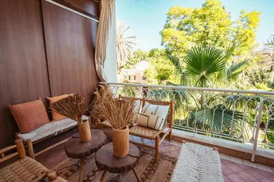 a balcony with a couch and chairs and a large window at vue imprenable sur les jardins de la villa d Yves saint Laurent in Marrakech