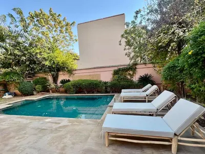 a pool with two lounge chairs and a large screen at Riad in Hotel M Avenue in Marrakech