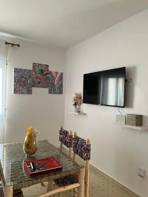 a dining room with a table and a television on the wall at Aeroport appartement in Marrakech