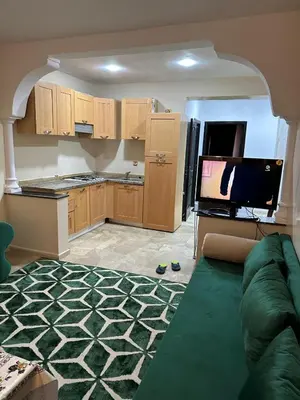 a living room with a couch and a kitchen at DARNA 34 FACE GARE CTM HIVERNAGE a 10MN DE L'AEROPORT in Marrakech