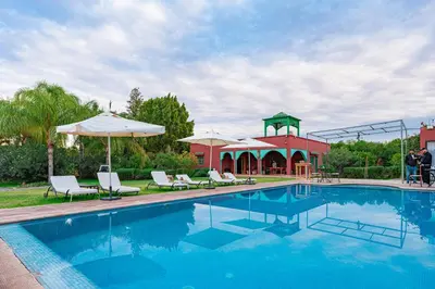 a swimming pool with chairs and a gazebo at Tente berbère in Marrakech