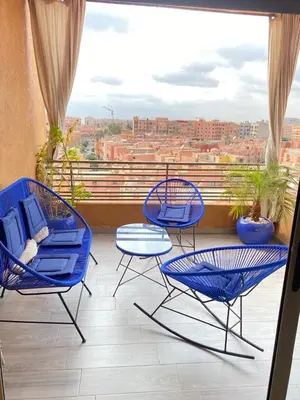a balcony with blue chairs and a table and a view at Kech Aliouni in Marrakech