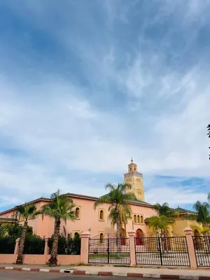 a building with a clock tower and palm trees at Angel 12 minutes from Marrakech airport in Marrakech