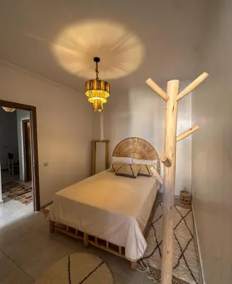 a bed with a wooden cross and a chandelier at A flat near the airport in Marrakech
