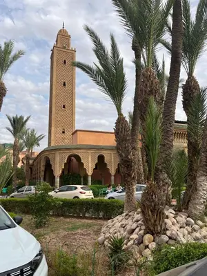 a building with a clock tower with palm trees in front at RIAD Marrakech zina in Marrakech