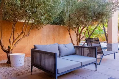 a couch and chairs on a patio with trees at Atelier Loft Oliver Palm Resort in Marrakech