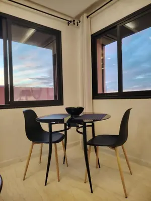 two tables and chairs in a room with windows at Modern apartement in Hivernage in Marrakech