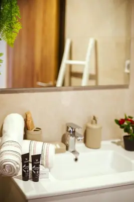 a bathroom sink with towels and a mirror at Livia cosy - Clim, Wifi, Jardin à 10min de l'Aéroport in Marrakech