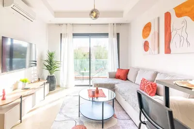 a living room with a couch and a table at Livia cosy - Clim, Wifi, Jardin à 10min de l'Aéroport in Marrakech