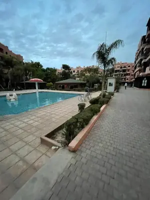 a swimming pool with a palm tree next to a building at appartement à coté des palmeraies in Marrakech