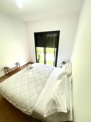 a bedroom with a large white bed with a window at Ana cosy - Clim, Wifi, Jardin à 10min de l'Aéroport in Marrakech