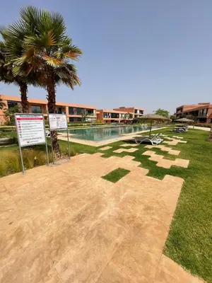 a resort with a pool and palm trees and a sign at Eva cosy - Clim, Wifi, Jardin à 10min de l'Aéroport in Marrakech