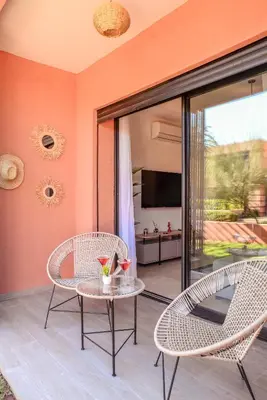 a patio with a table and chairs and a television at Lina cosy - Clim, Wifi, Jardin à 10min de l'Aéroport in Marrakech