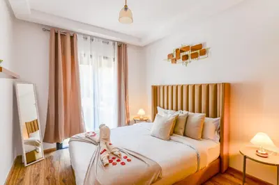 a bedroom with a large bed with two dolls on it at Lina cosy - Clim, Wifi, Jardin à 10min de l'Aéroport in Marrakech