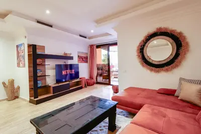 a living room with a red couch and a mirror at La Kasbah - 2bdr- Parking - Wifi - Terrasse in Marrakech