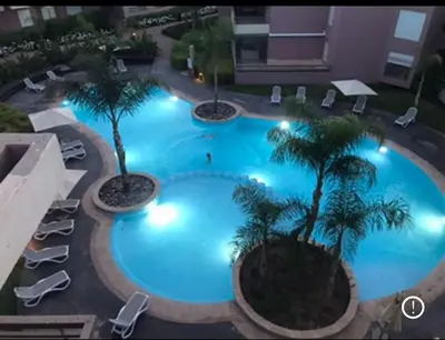 an overhead view of a large swimming pool with palm trees at Appartement familial in Marrakech