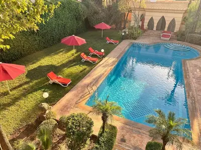 a swimming pool with red umbrellas and chairs and a pool at Charming Luxury Villa - Pool & Hot Tub in Marrakech