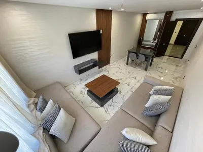 a living room with a couch and a flat screen tv at Palmeraie Appart B4 Piscine & Parking in Marrakech