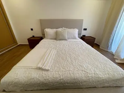 a large white bed with white sheets and pillows at Palmeraie Appart B4 Piscine & Parking in Marrakech