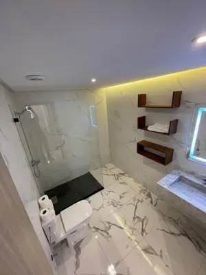a white bathroom with a toilet and a window at Palmeraie Appart B4 Piscine & Parking in Marrakech