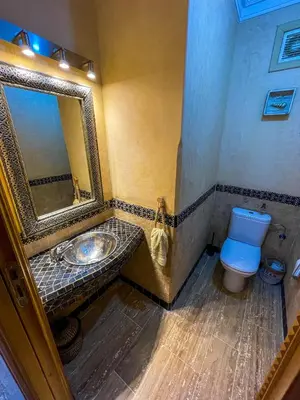 a bathroom with a sink and a toilet and a mirror at Stunning Patios & Gardens Apartment in Marrakech