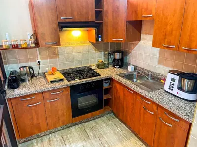 a kitchen with wooden cabinets and a stove top oven at Stunning Patios & Gardens Apartment in Marrakech