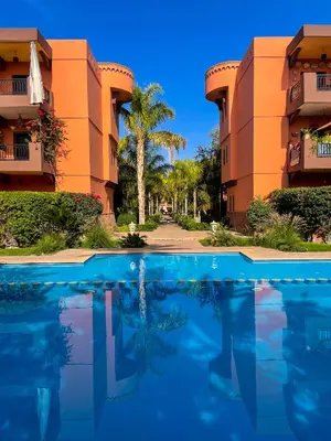 a swimming pool in front of two apartment buildings at Stunning Patios & Gardens Apartment in Marrakech